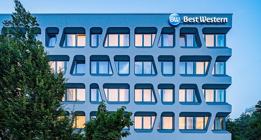 Außenansicht eines modernen Best Western Hotels mit markanter Fassade und beleuchteten Fenstern in der Abenddämmerung