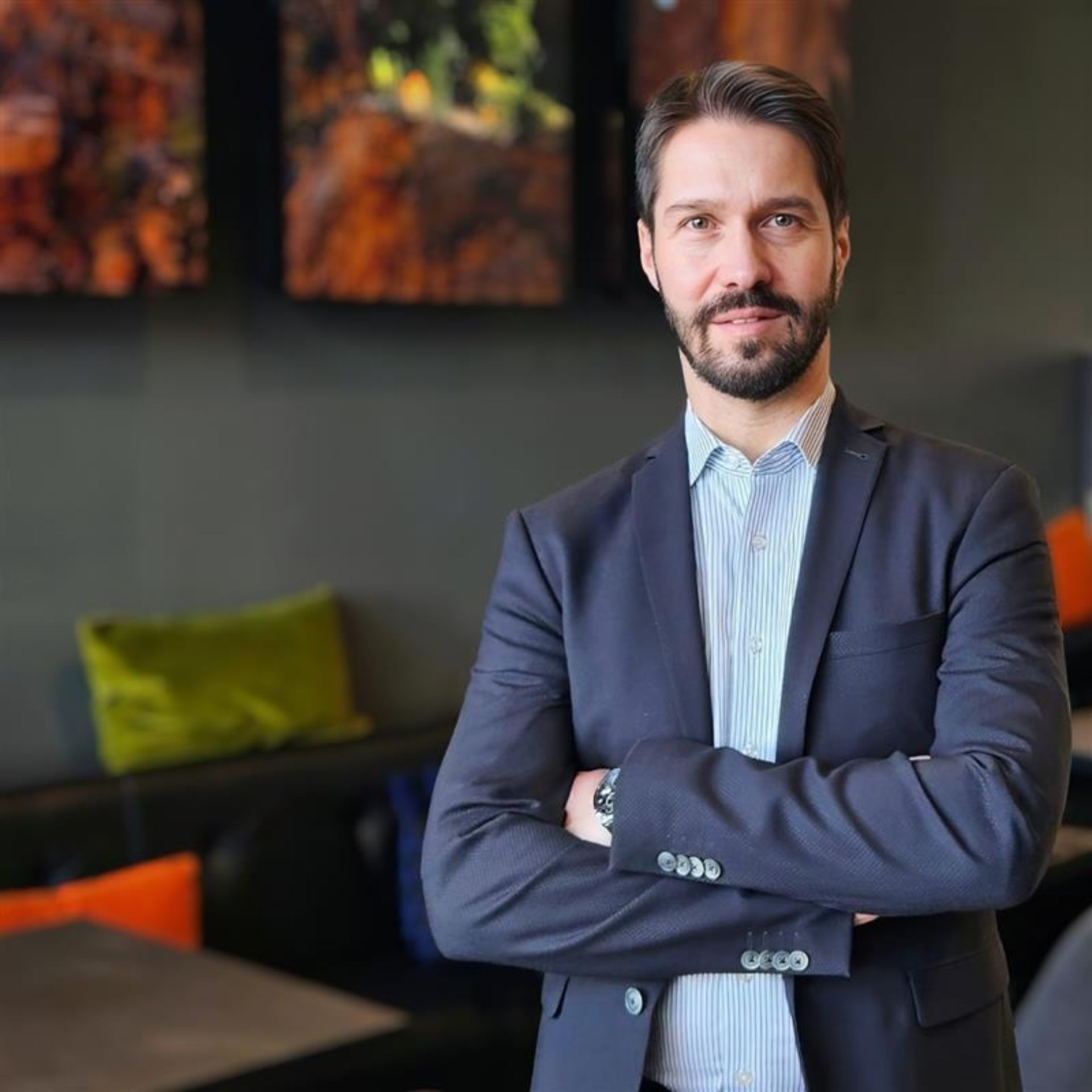 Sascha Brezovac, lächelnd mit verschränkten Armen in der modernen Lobby eines Best Western Hotels. Die helle und freundliche Atmosphäre unterstreicht seine professionelle und einladende Ausstrahlung